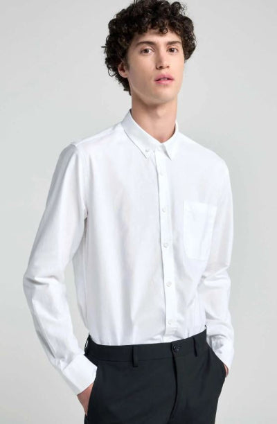 Man wearing a white dress shirt and black pants against a plain background